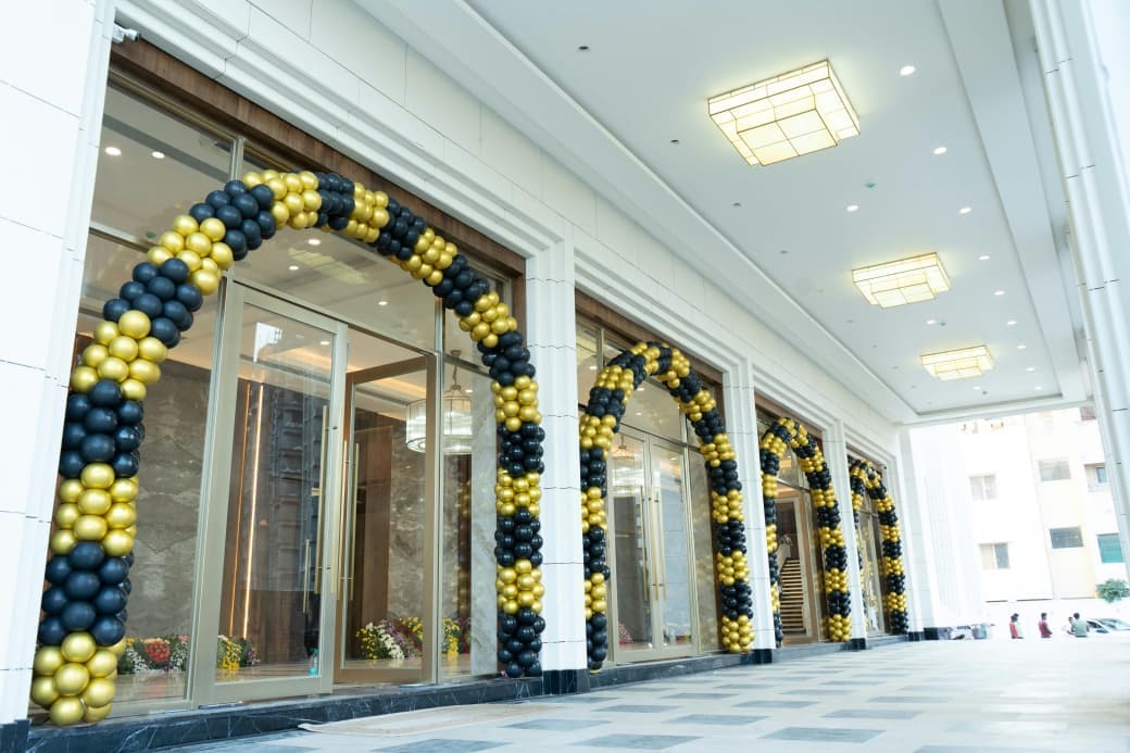 A run of black and gold balloon arches along the entrance arcade