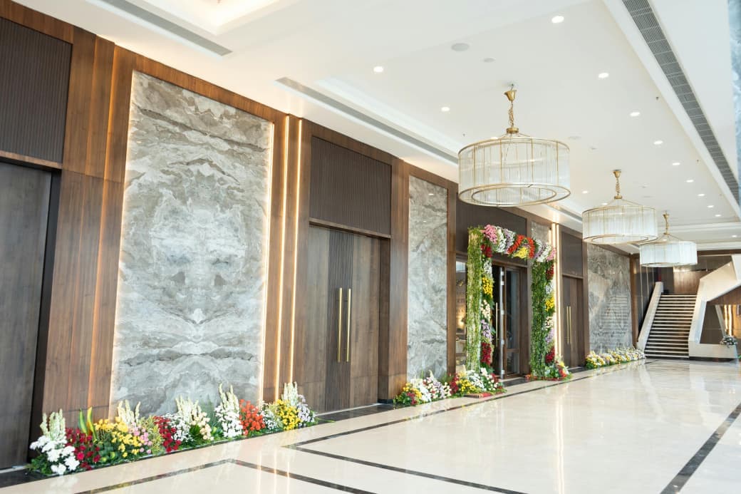 Lobby corridor under drum chandeliers, flowers banked along the marble wall