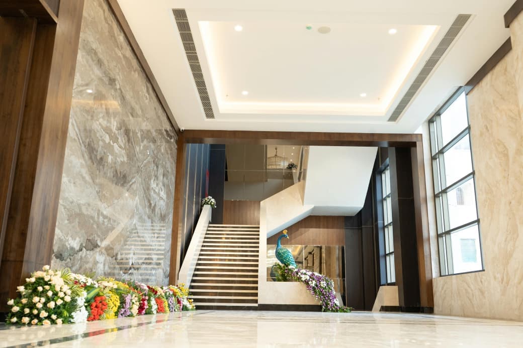 Stair hall with a peacock sculpture and cascading flowers at the foot of the staircase