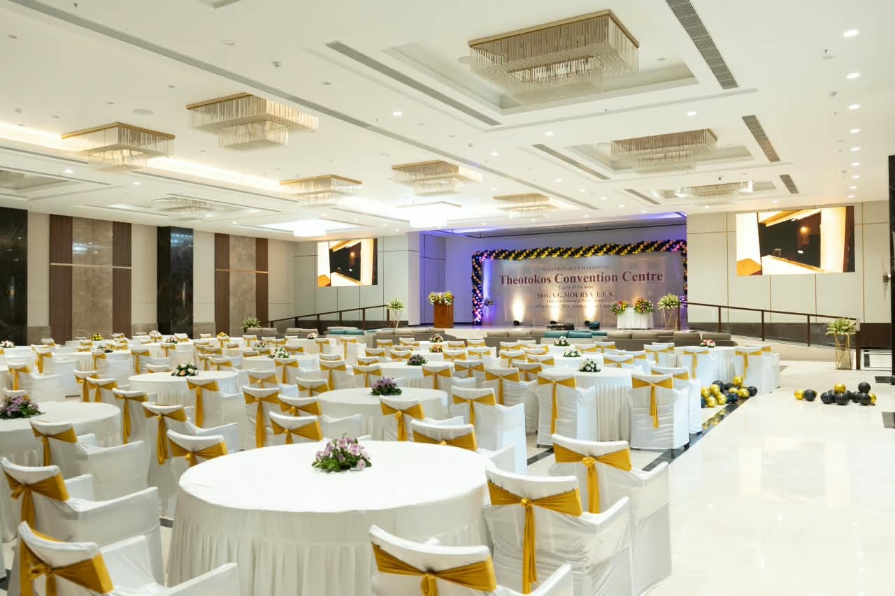 Banquet hall set with round tables and gold-sashed chairs, facing the inauguration stage
