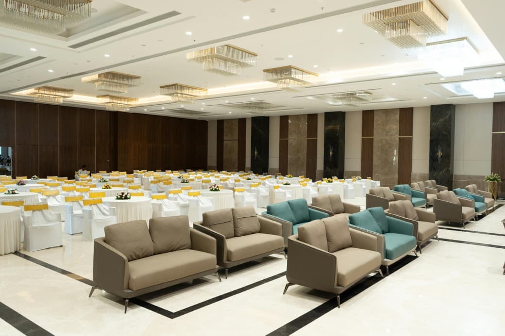 Rows of taupe and teal sofas for guests in front of the banquet tables