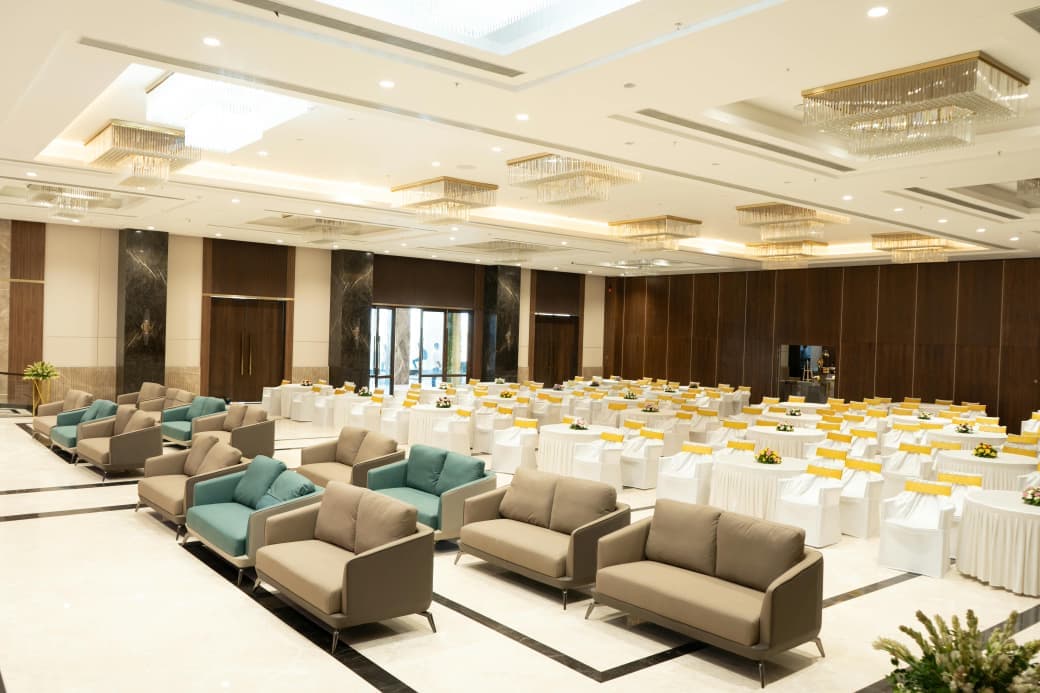 Sofa seating and dining tables filling the hall under crystal chandeliers