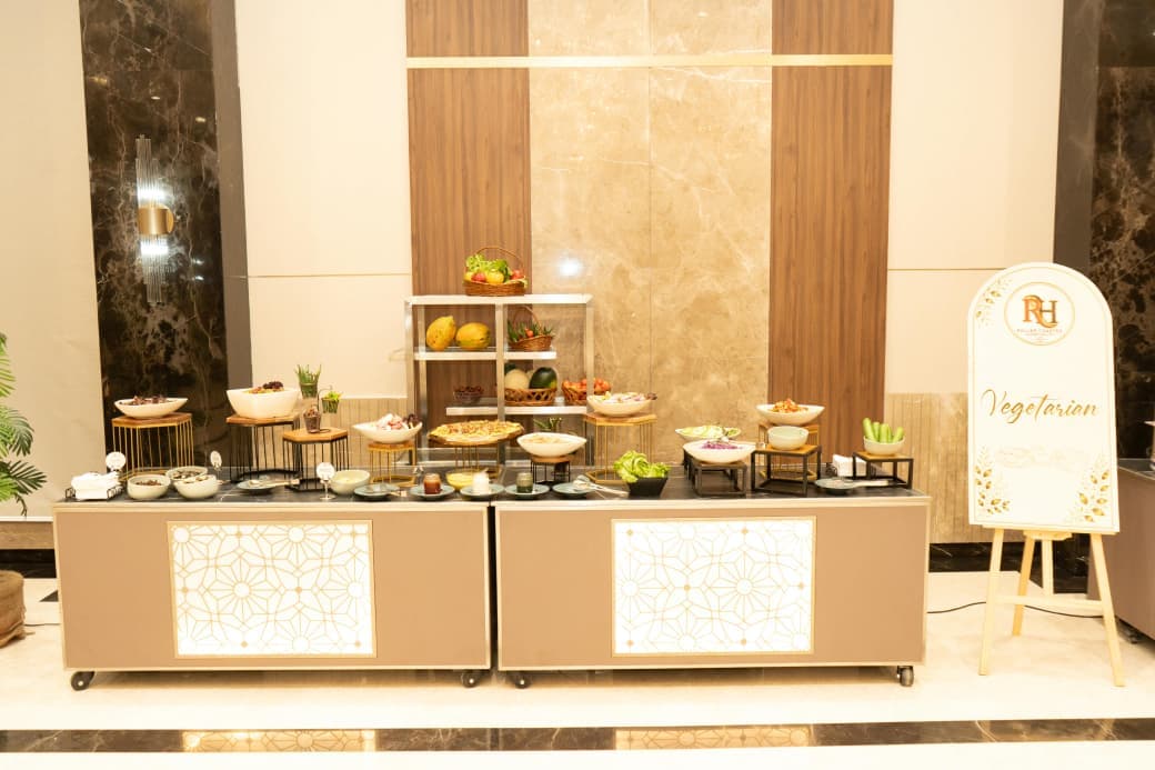 Vegetarian buffet counter with salads, fruit baskets and a signboard