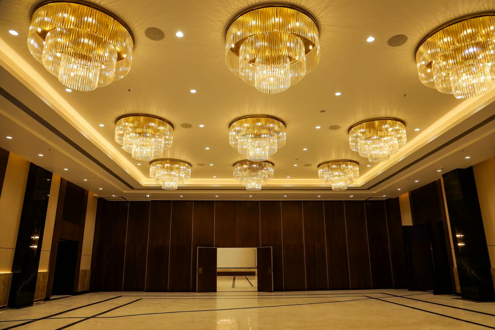 Tiered chandeliers above the Antonios hall floor, with the teak partition wall behind