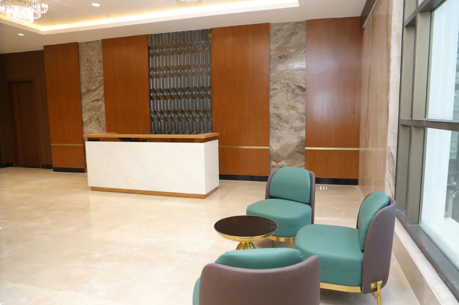 Waiting lounge with teal armchairs and a marble reception counter