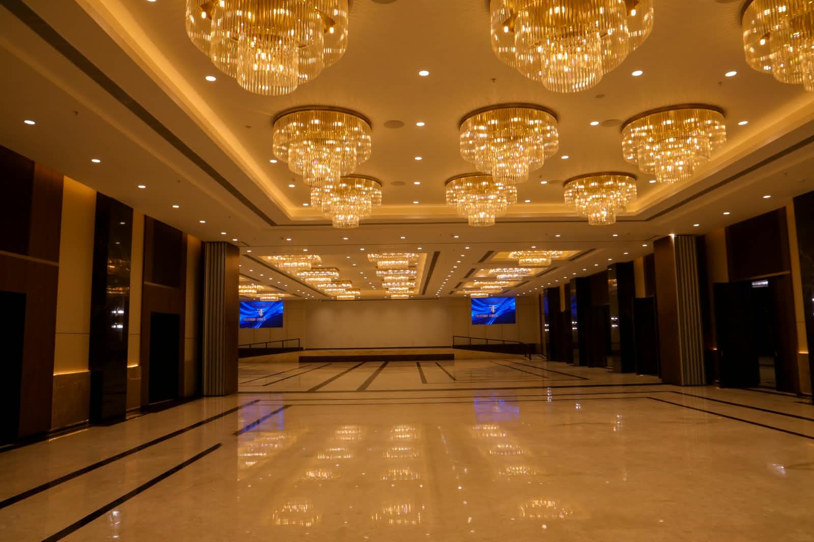 The full length of Dominikos hall, chandeliers reflected in the marble floor